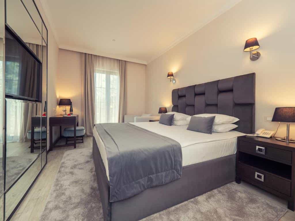 Hotel room with large bed, mirrored wardrobe, and desk near balcony doors in Hotel Moskva Budva.