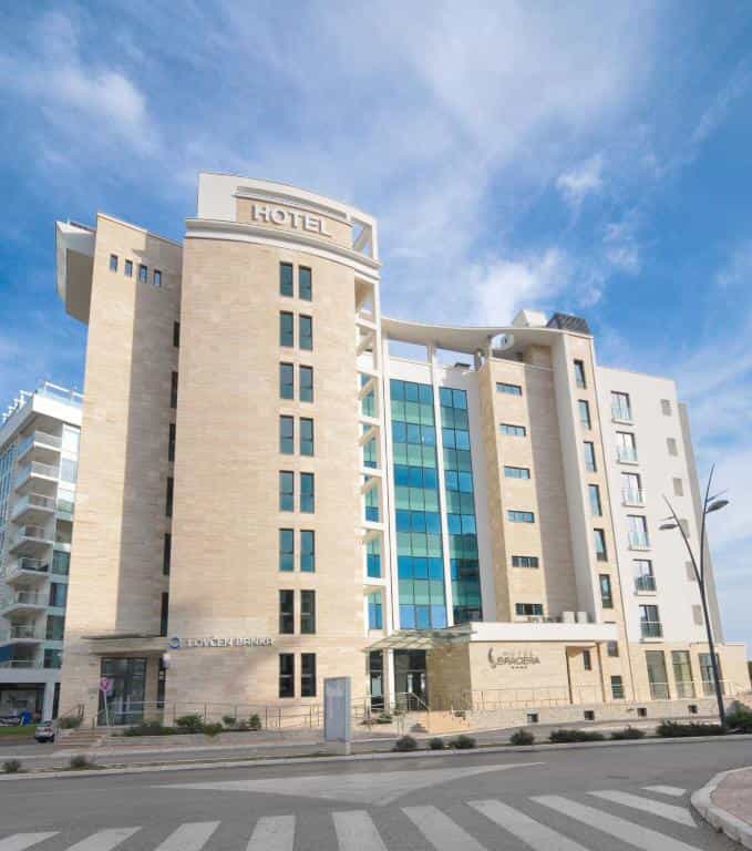Hotel Bracera building with modern stone facade and blue glass windows under a bright sky.