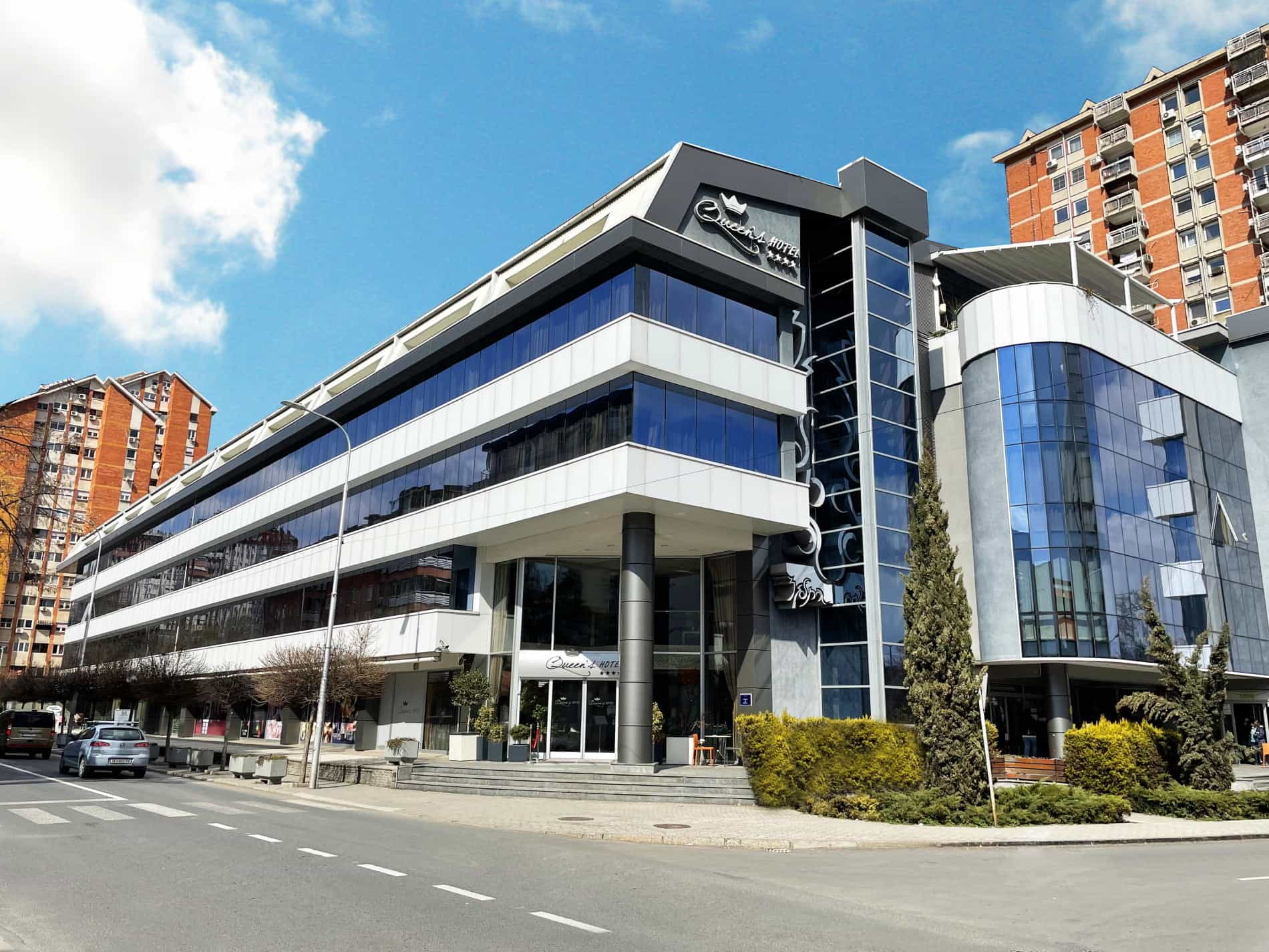 Queen's Hotel building with modern glass facade on city street, Skopje.