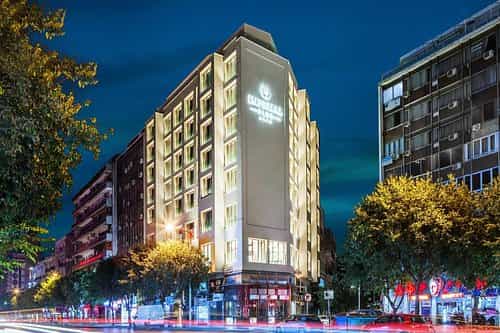 Imperial Plus Urban Smart Hotel Thessaloniki exterior at night with light trails on city street.