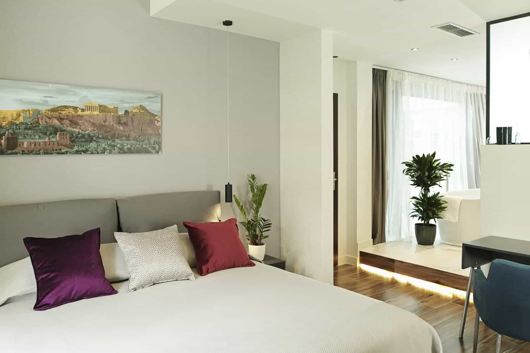 Modern hotel bedroom with Acropolis artwork and raised bathtub area, Gem Society Hotel Athens.