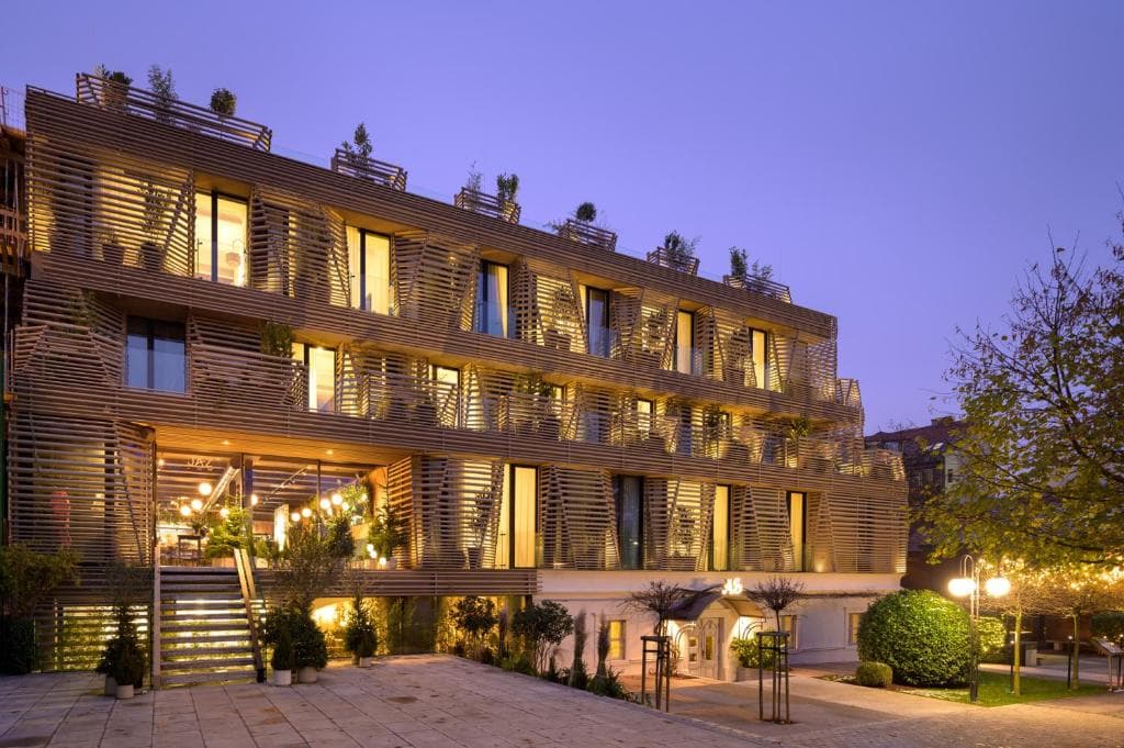 Boutique hotel exterior with modern wooden facade illuminated at dusk in Ljubljana.